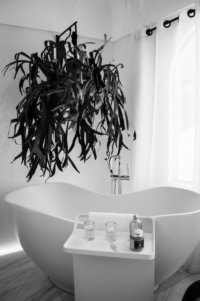 grayscale photography of bathtub near window